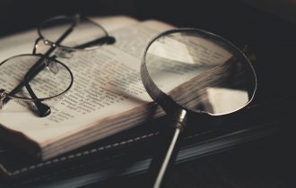 a magnifying glass and a pair of glasses lying on a book