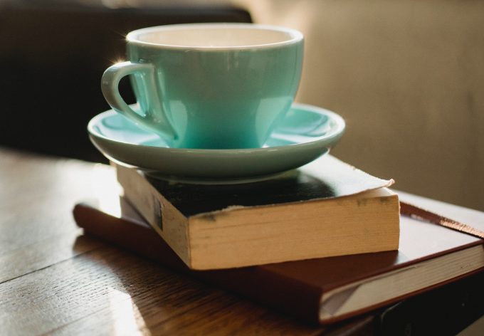 a green coffee cup sitting on a book