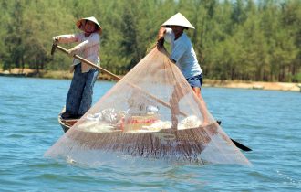 two Vietnamese fisherman fishing in a traditional manner