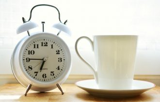 a coffee cup next to an alarm clock