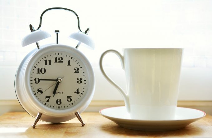 a coffee cup next to an alarm clock