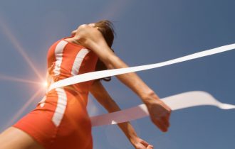 Low,Angle,View,Of,Young,Female,Athlete,Crossing,Finish,Line