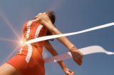 Low,Angle,View,Of,Young,Female,Athlete,Crossing,Finish,Line