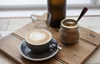 a cup of coffee sits on a wooden board