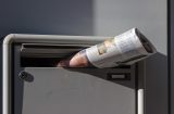 a newspaper poking through a letterbox