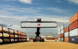 a shipping container branded dli being held aloft in a logistics facility 230907 iip dli