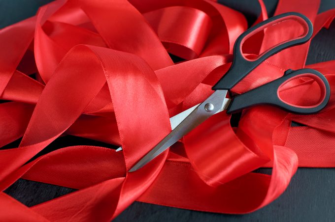 a pair of scissors cutting a red ribbon