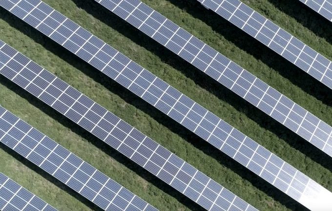 a view of rows of solar panels in a grassy field from above