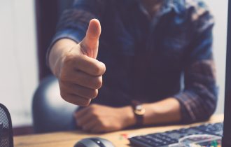a man sitting at a desk with his thumb up