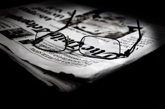 a pair of glasses sitting on the corner of a newspaper