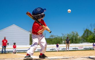 little league baseball player about to hit a ball