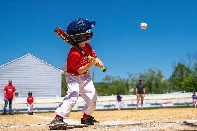 little league baseball player about to hit a ball