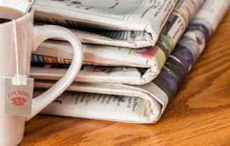 the side of a mug in front of a stack of newspapers