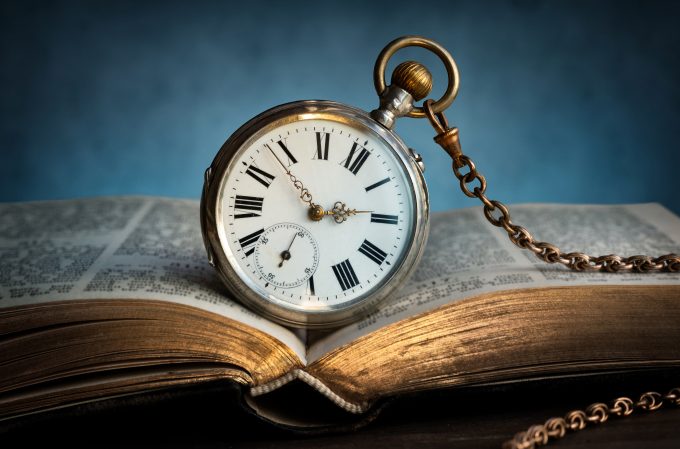 a pocket watch sits on an open book