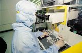 Inside an 8-inch wafer fab - person with vision-enhancing goggles in protective suit examining product