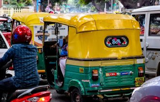 yellow and green tuktuk in crowded traffic in Bengaluru