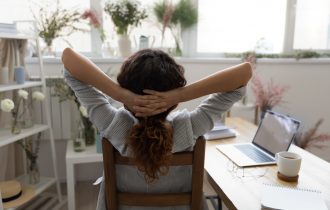 woman with our back to us sits next to a near-empty desk gazing out of the window