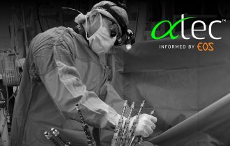 a surgeon clutches what looks like a clamp - one of a number protruding from the patient's spine (but we cropped that bit out)