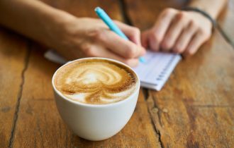 cup of coffee and someone taking notes on a pad