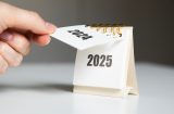 a woman's hand tearing off 2024 from a calendar to reveal 2025