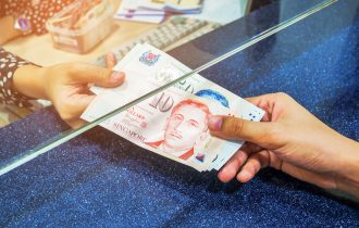 one person hands over singapore dollars to another in a bank