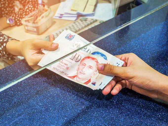 one person hands over singapore dollars to another in a bank