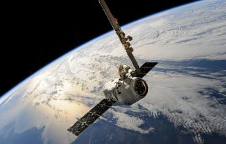 a computer generated image of a satellite in space with the Earth visible behind it