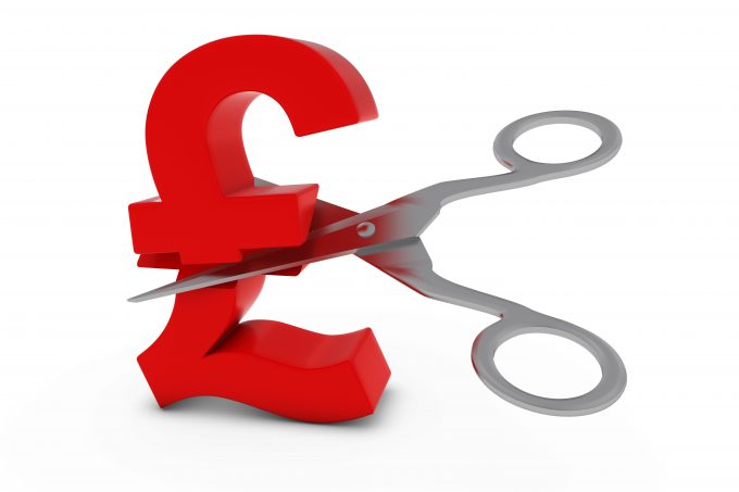 a red pound sign being cut by a pair of metal scissors