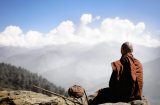 a monk looks out across a valley