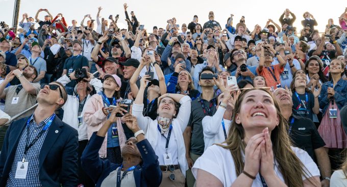 an excited crowd stares upward as Artemis 2 mission takes off