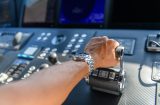 a close up view of a hand pushing on a throttle to make an engine (probably a boat) go faster