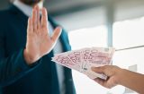 someone has their hand up refusing the offer of a spread of 500 euro notes